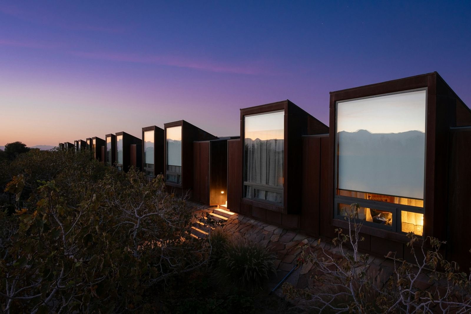 Row of glass-fronted modular cabins glowing at dusk